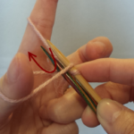 人差し指の糸を矢印の様に２本の針の間に通してメインの針にかけます。